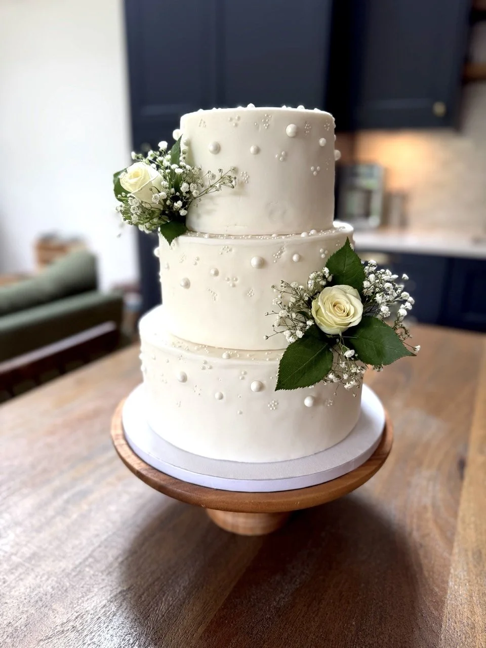Bespoke three-tier white wedding cake with fresh white roses and pearl details handcrafted by The Cake Lady Cambridge